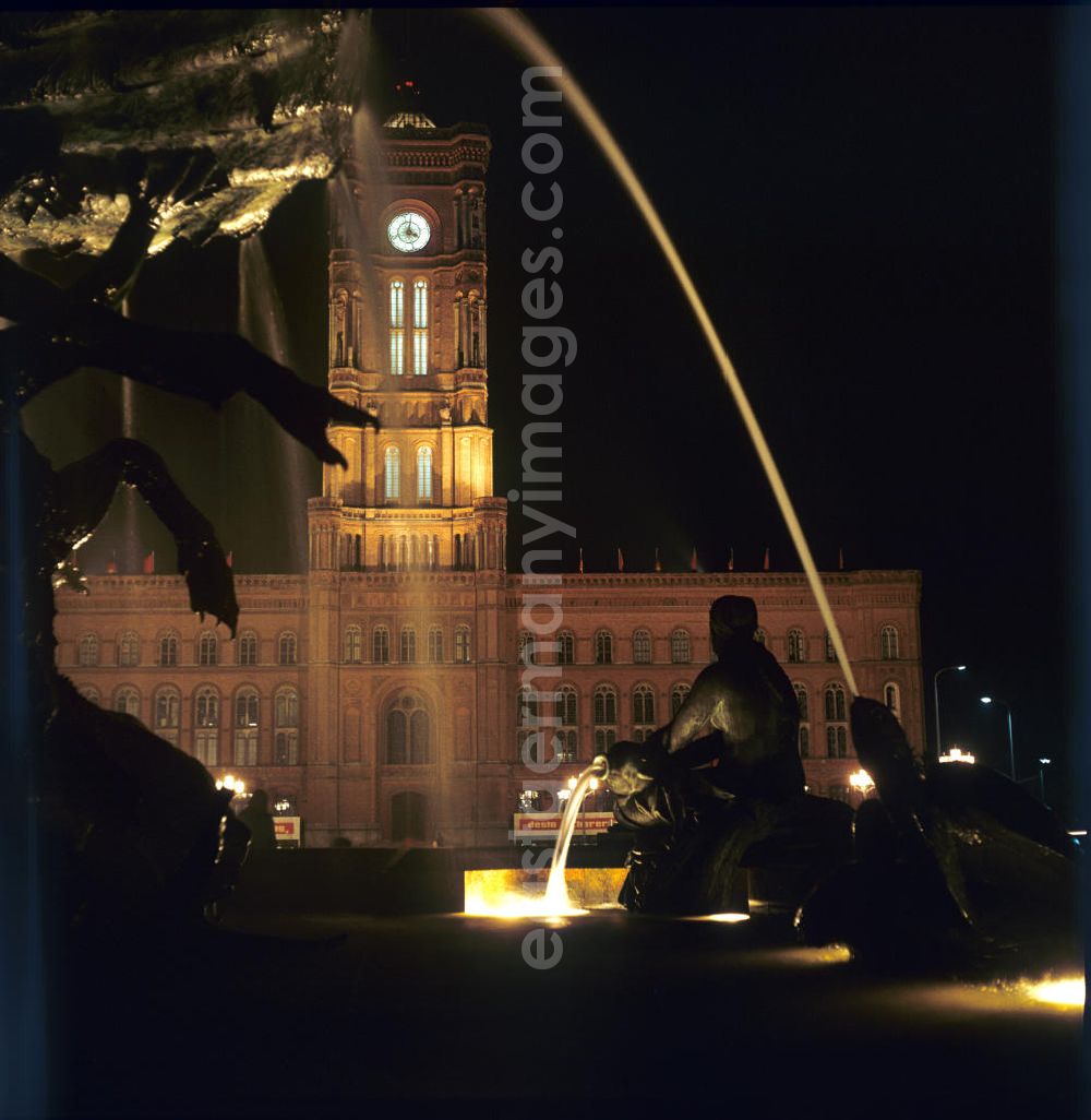 Aerial photograph at night Berlin - Nachtaufnahme: Blick durch die Wasserfontänen des Neptunbrunnens auf das Rote Rathaus in Berlin-Mitte am Jahrestag der DDR. Mit der Errichtung des Fernsehturms sowie der Umgestaltung seiner Umgebung Mitte der 6