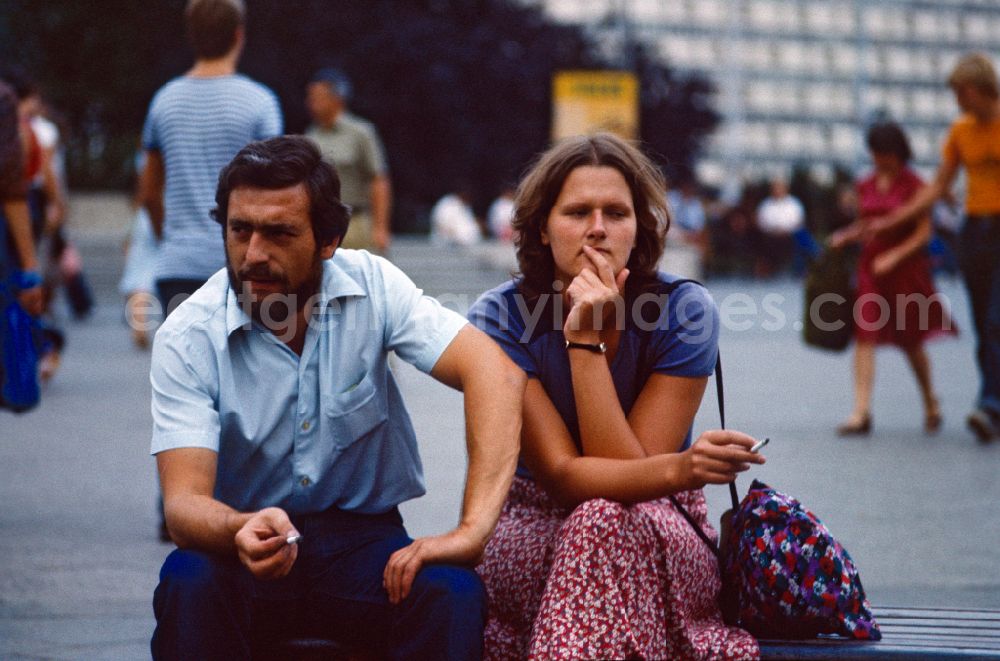 GDR image archive: Berlin - Woman and man sitting smoking on a street bench at Alexanderplatz in East Berlin in the territory of the former GDR, German Democratic Republic