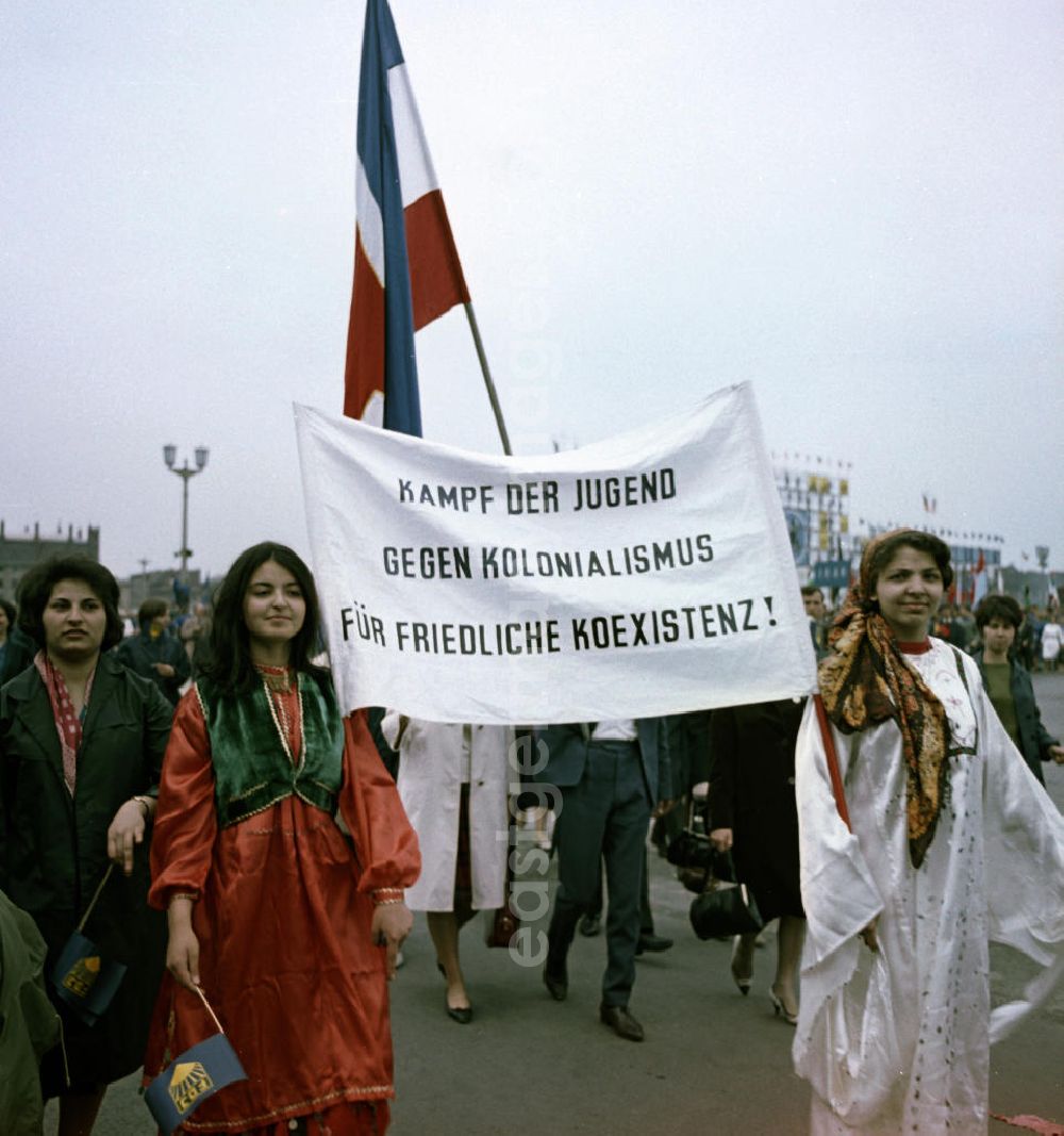 Berlin: Zu Pfingsten 1964, vom 16.-18. Mai, findet in Berlin das letzte Deutschlandtreffen der Jugend für Frieden und Völkerfreundschaft statt, hier laufen ausländische Teilnehmerinnen mit einem Transparent mit der Aufschrift Kampf der Jugend gegen Kolonialismus für friedliche Koexistenz! vor der Ehrentribüne auf dem Marx-Engels-Platz (heute Schloßplatz) vorbei. Nach 1964 entsprach eine gesamtdeutsche kommunistische Politik nicht mehr den Zielen der DDR-Regierung. In den 70er und 8