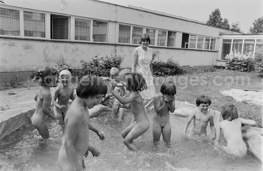 GDR photo archive: Berlin - Play and fun with small children supervised by educators in a kindergarten splashing around in a water basin on the street Rosenfelder Ring in the district of Lichtenberg in Berlin East Berlin in the area of the former GDR, German Democratic Republic