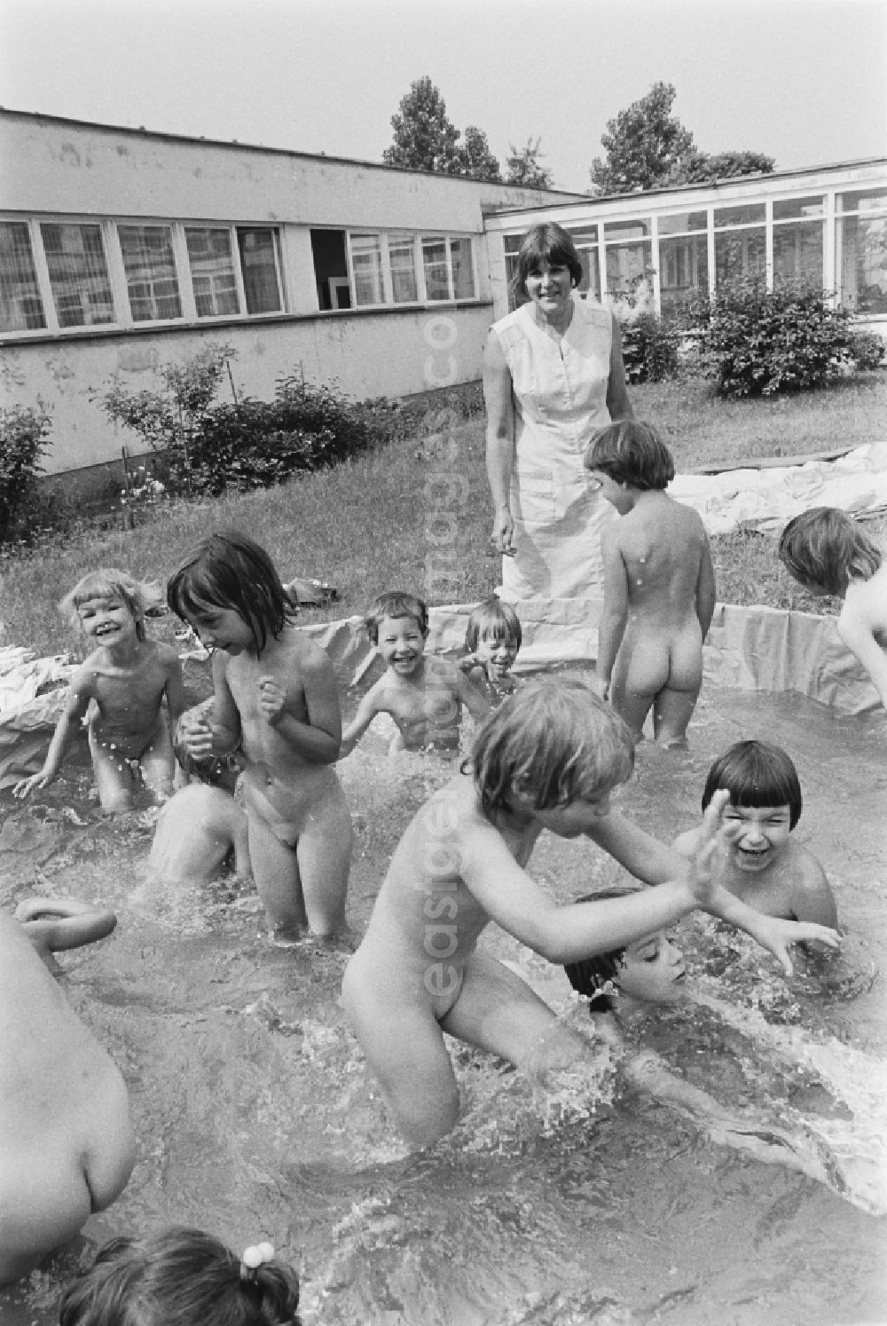 Berlin: Play and fun with small children supervised by educators in a kindergarten splashing around in a water basin on the street Rosenfelder Ring in the district of Lichtenberg in Berlin East Berlin in the area of the former GDR, German Democratic Republic