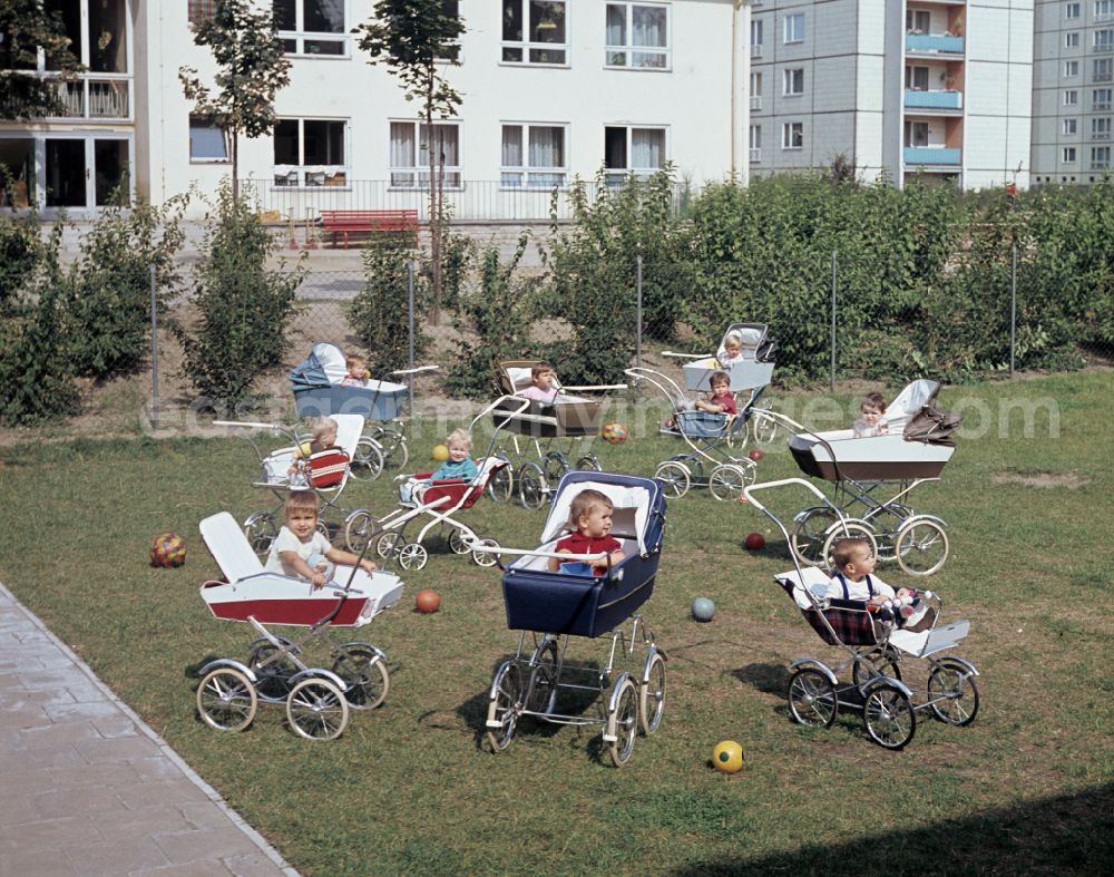 GDR image archive: Berlin - Small children sit in a stroller in the yard of a daycare center in East Berlin in the territory of the former GDR, German Democratic Republic