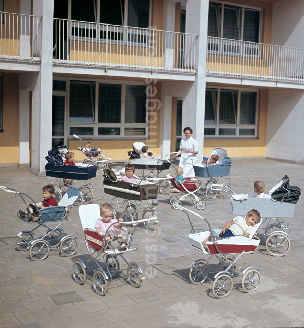 GDR photo archive: Berlin - Small children sit in a stroller in the yard of a daycare center in East Berlin in the territory of the former GDR, German Democratic Republic