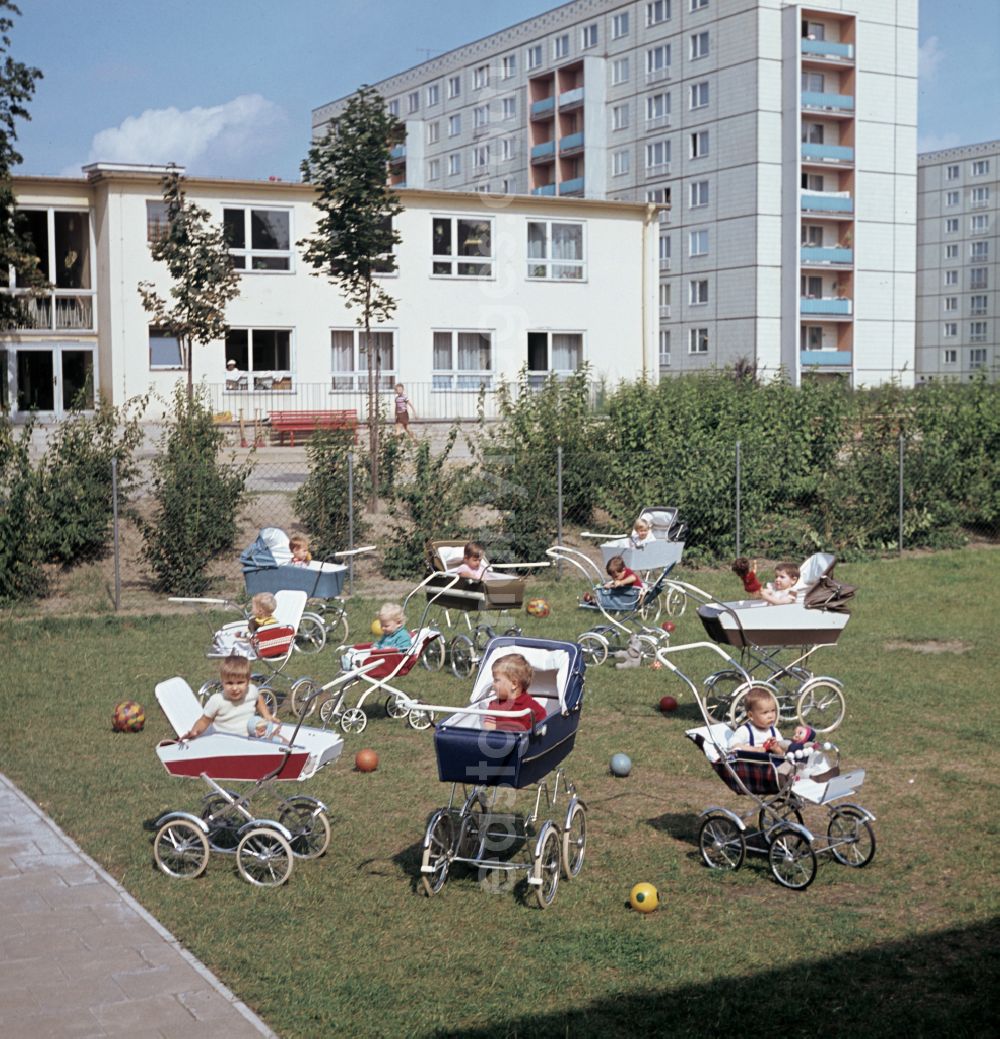 GDR picture archive: Berlin - Small children sit in a stroller in the yard of a daycare center in East Berlin in the territory of the former GDR, German Democratic Republic