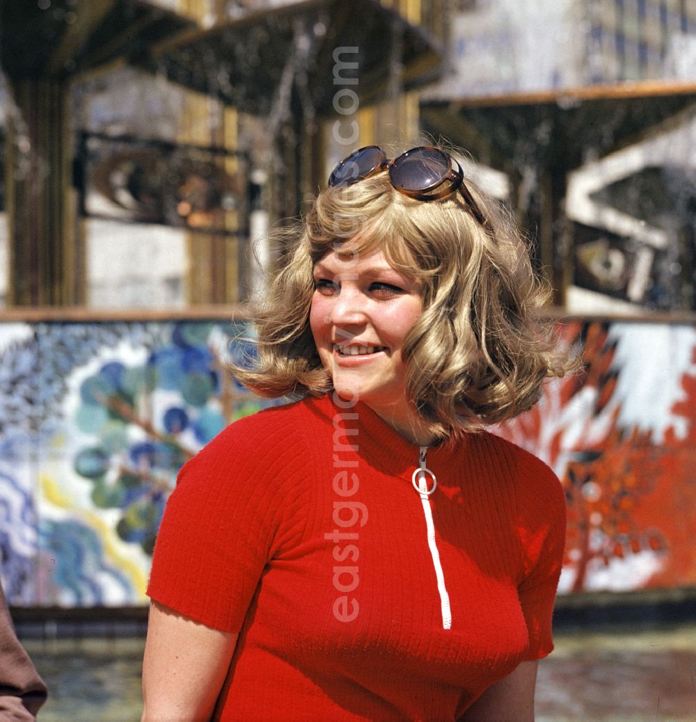 GDR image archive: Berlin - A young woman sits on the edge of the Fountain of Friendship of Peoples at Alexanderplatz in the Mitte district of East Berlin in the territory of the former GDR, German Democratic Republic