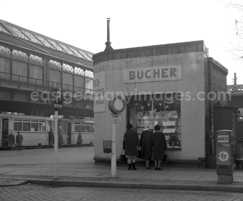 GDR photo archive: Berlin - Die Schönhauser Allee in Berlin-Prenzlauer Berg gehört zu den beliebtesten Einkaufsstraßen im Berliner Osten, hier betrachten drei Frauen die Schaufensterauslage der Buchhandlung Walter Woelke an der Schönhauser Allee / Ecke Dänenstraße. Im Hintergrund steigen Passanten in die Straßenbahn, die U-Bahnlinie verläuft auch heute noch entlang der Schönhauser Allee über der Erde.