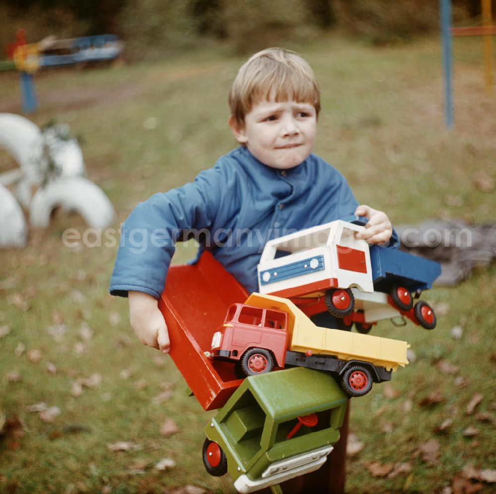 GDR photo archive: Bad Saarow - Im Kinderheim Bad Saarow trägt ein Junge Spielzeuglaster auf seinem Arm.