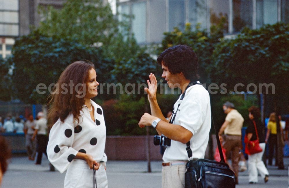 Berlin: Photographer talking to a young woman on Alexanderplatz in East Berlin in the territory of the former GDR, German Democratic Republic