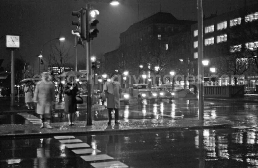 GDR photo archive: Berlin - Pedestrians and passers-by in traffic in the night rain on street Friedrichstrasse, Ecke Unter den Linden in Berlin Eastberlin on the territory of the former GDR, German Democratic Republic