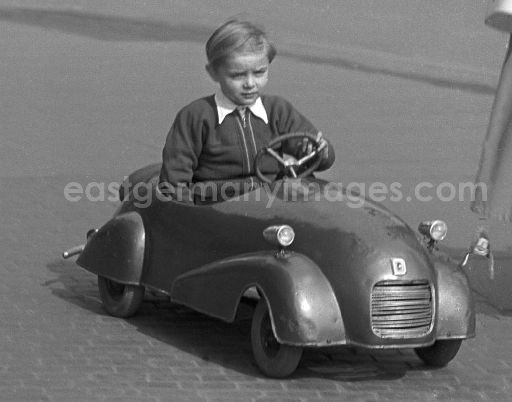 GDR image archive: Leipzig - Stolz fährt dieser Junge mit seinem Automobil bei einem Sonntagsspaziergang auf einer Straße in Leipzig.