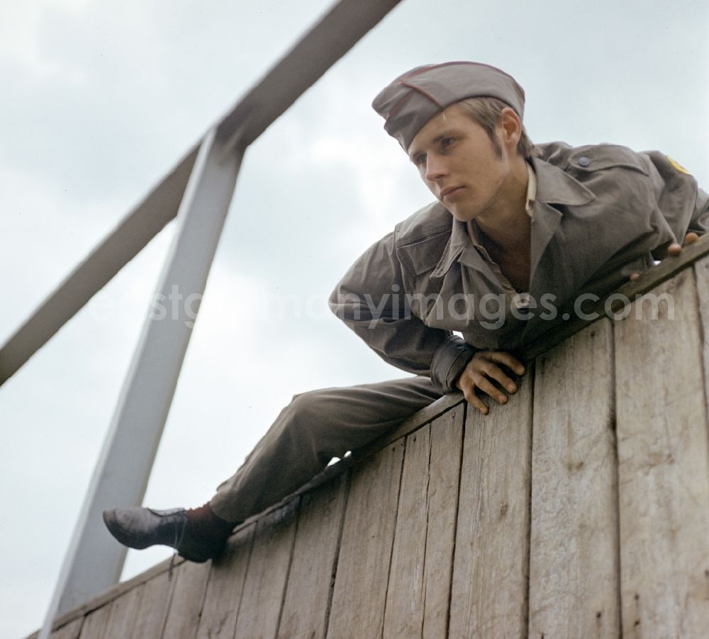 Berlin: Young man overcomes an escalator wall during pre-military training on the Sturmbahn as part of the Society for Sports and Technology in Berlin, East Berlin in the territory of the former GDR, German Democratic Republic