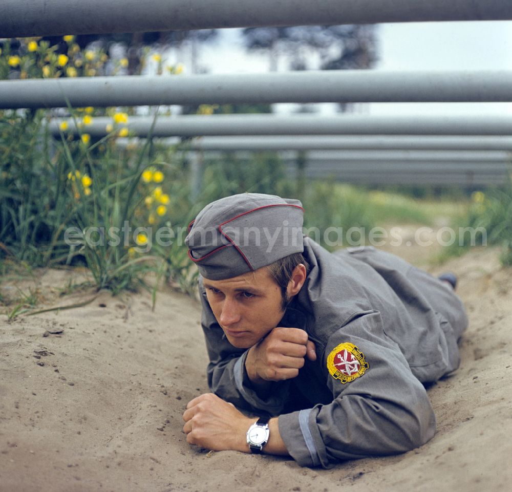 GDR image archive: Berlin - Young man overcomes a ground obstacle during pre-military training on the Sturmbahn as part of the Society for Sports and Technology in Berlin, East Berlin in the territory of the former GDR, German Democratic Republic