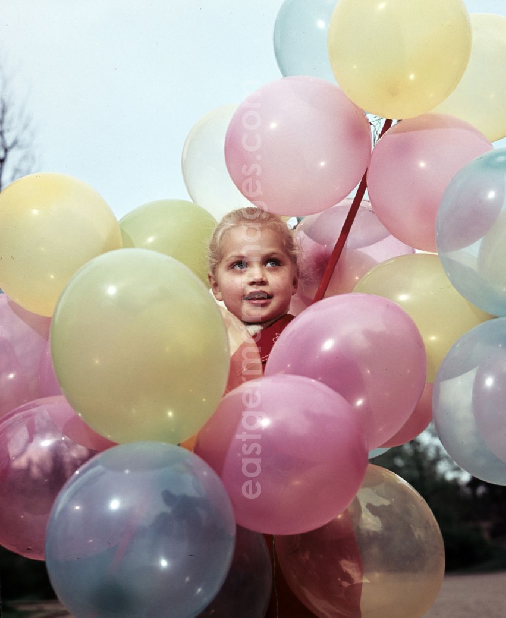 Coswig: Girl with balloons in a stroller in Coswig, Saxony in the territory of the former GDR, German Democratic Republic