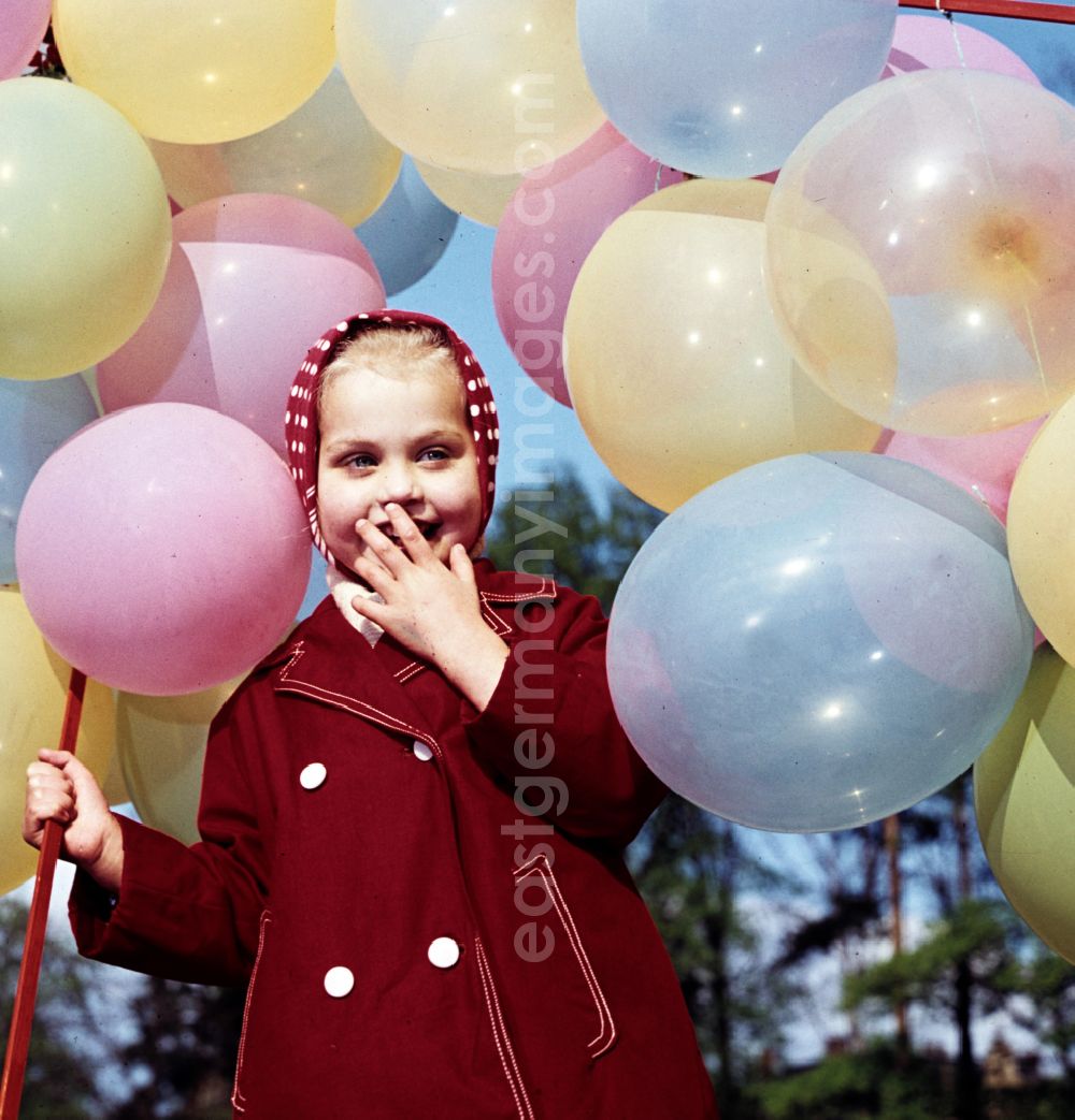 GDR photo archive: Coswig - Girl with balloons in a stroller in Coswig, Saxony in the territory of the former GDR, German Democratic Republic