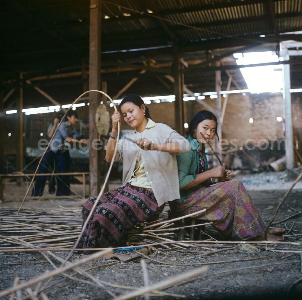 GDR picture archive: Vientiane - Frauen bei der Arbeit in einer Bambusmöbelfabrik in Vientiane in der Demokratischen Volksrepublik Laos.