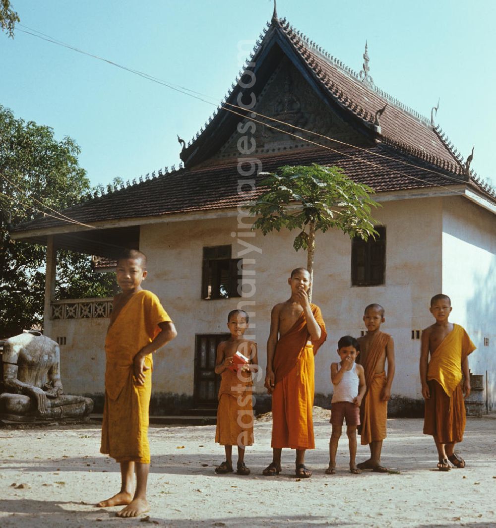 Vientiane: Kindermönche / Mönche in den charakteristischen safrangelben Gewändern in einem buddhistischen Tempel in Vientiane, der Hauptstadt der Demokratischen Volksrepublik Laos. Bis zur Ausrufung der Volksrepublik Laos am 2. Dezember 1975 bestimmte der Theravada-Buddhismus die kulturelle Entwicklung im Land. Nachdem die anfängliche Unterdrückung der traditionellen buddhistischen Bräuche durch die neuen kommunistischen Machthaber mißlang, fand Laos in den folgenden Jahrzehnten einen eigenen Weg der Koexistenz von Buddhismus und Sozialismus.