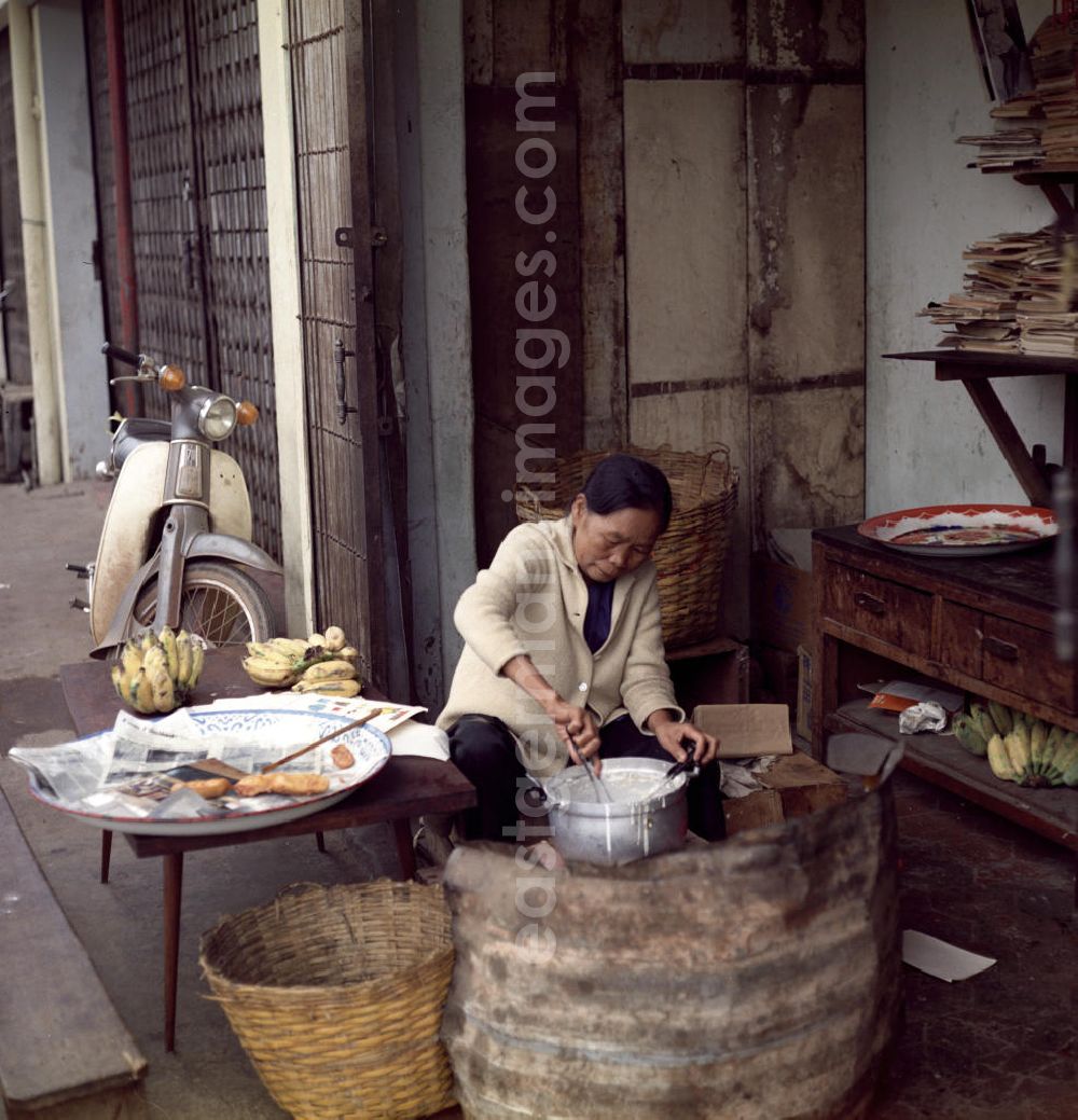 GDR photo archive: Vientiane - Eine Frau kocht Essen am Rande einer Straße in Vientiane in der Demokratischen Volksrepublik Laos.