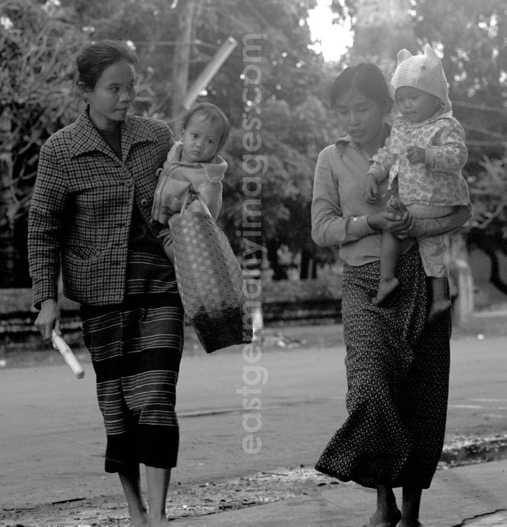 GDR picture archive: Vientiane - Frauen mit Kindern überqueren eine Straße in Vientiane in der Demokratischen Volksrepublik Laos.