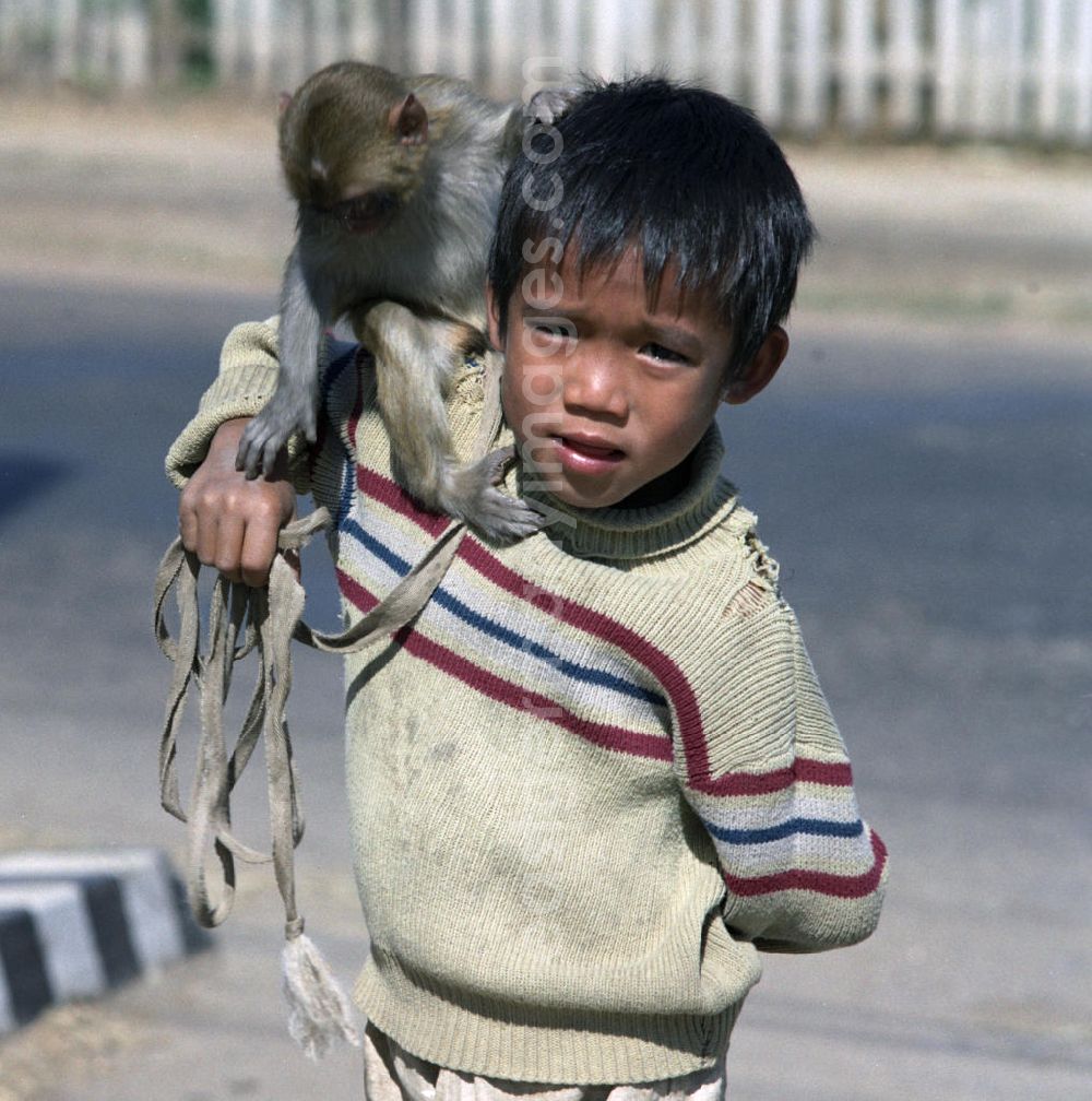 GDR image archive: Vientiane - Ein Junge mit einem Affen auf seiner Schulter steht auf einer Straße in Vientiane, der Hauptstadt der Demokratischen Volksrepublik Laos.