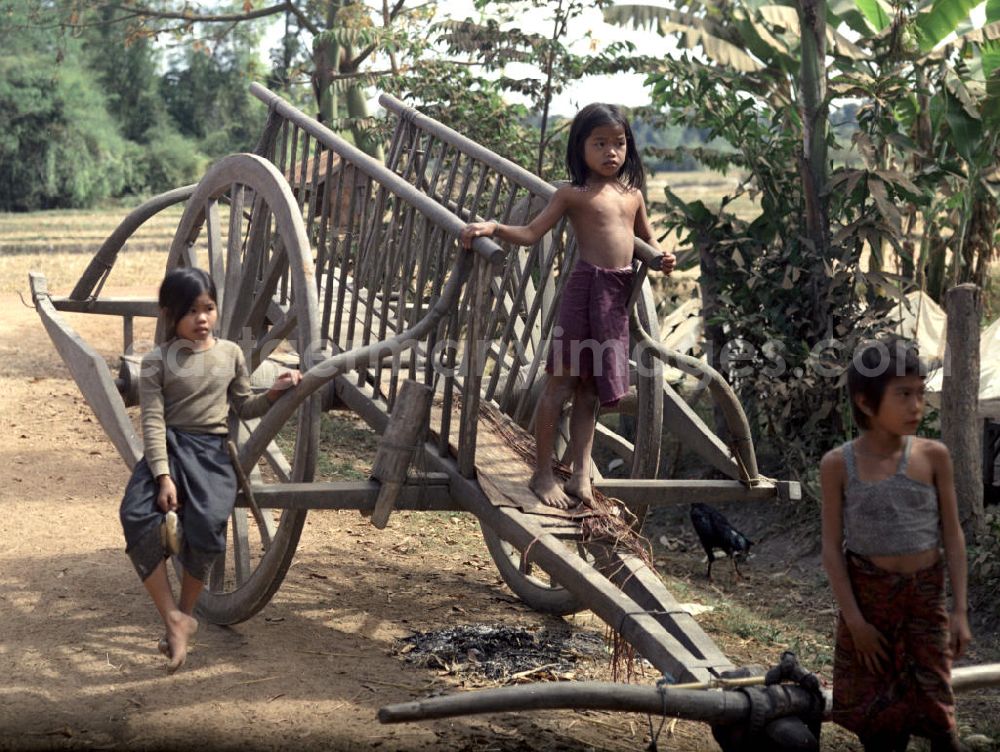 GDR picture archive: Vientiane - Kinder auf einem Karren in einem Dorf in der Demokratischen Volksrepublik Laos.