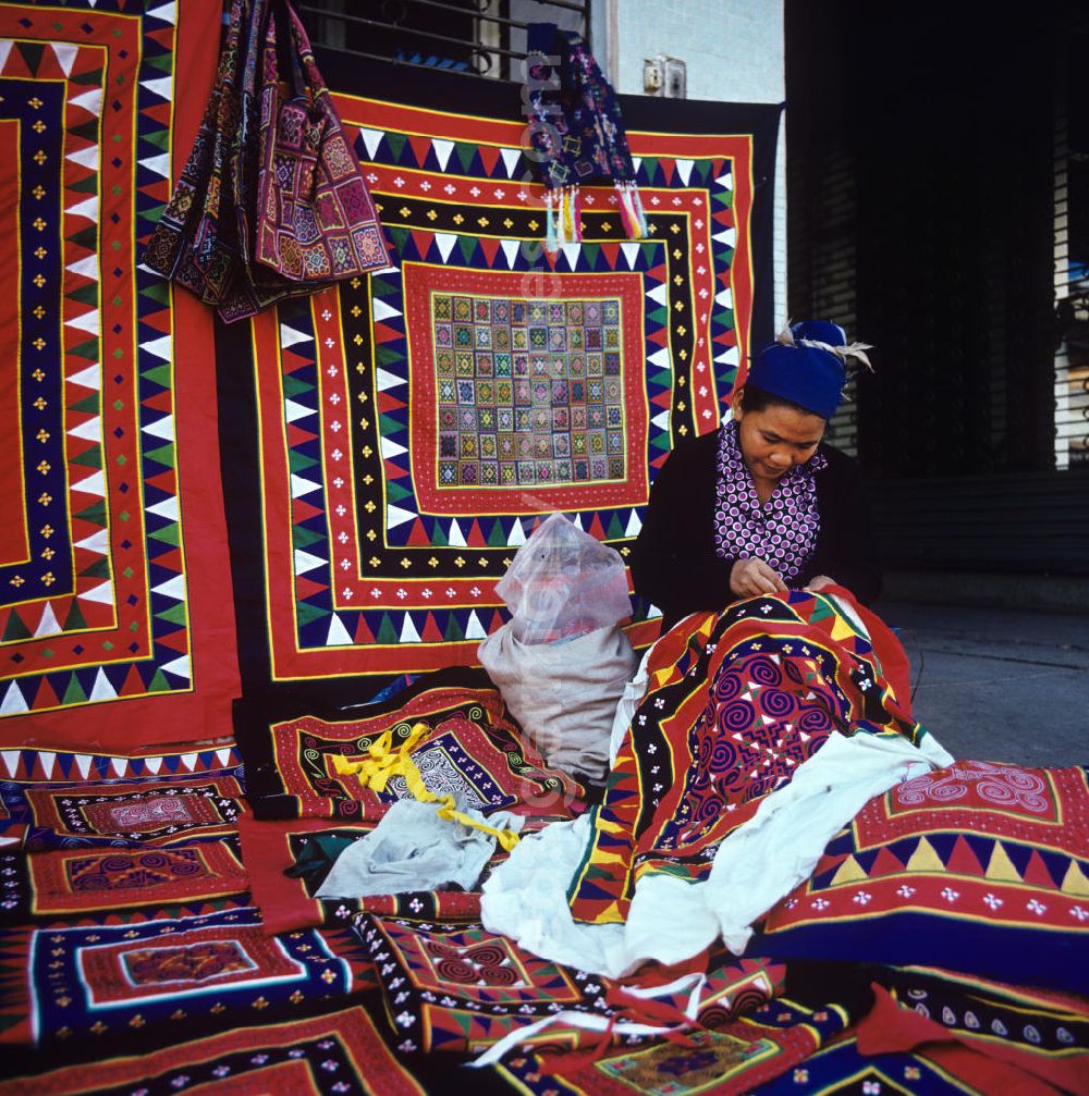 GDR image archive: Vientiane - Eine Frau aus dem Volksstamm der Meo, auch Hmong genannt, verkauft selbstgenähte Decken in Vientiane, der Hauptstadt der Demokratischen Volksrepublik Laos. Die Hmong gehörten zu einer infolge des Vietnam-Krieges verfolgten und zurückgezogen lebenden Minderheit in Laos.