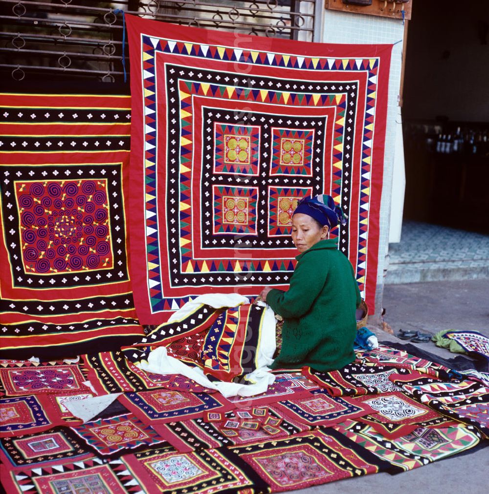 GDR photo archive: Vientiane - Eine Frau aus dem Volksstamm der Meo, auch Hmong genannt, verkauft selbstgenähte Decken in Vientiane, der Hauptstadt der Demokratischen Volksrepublik Laos. Die Hmong gehörten zu einer infolge des Vietnam-Krieges verfolgten und zurückgezogen lebenden Minderheit in Laos.