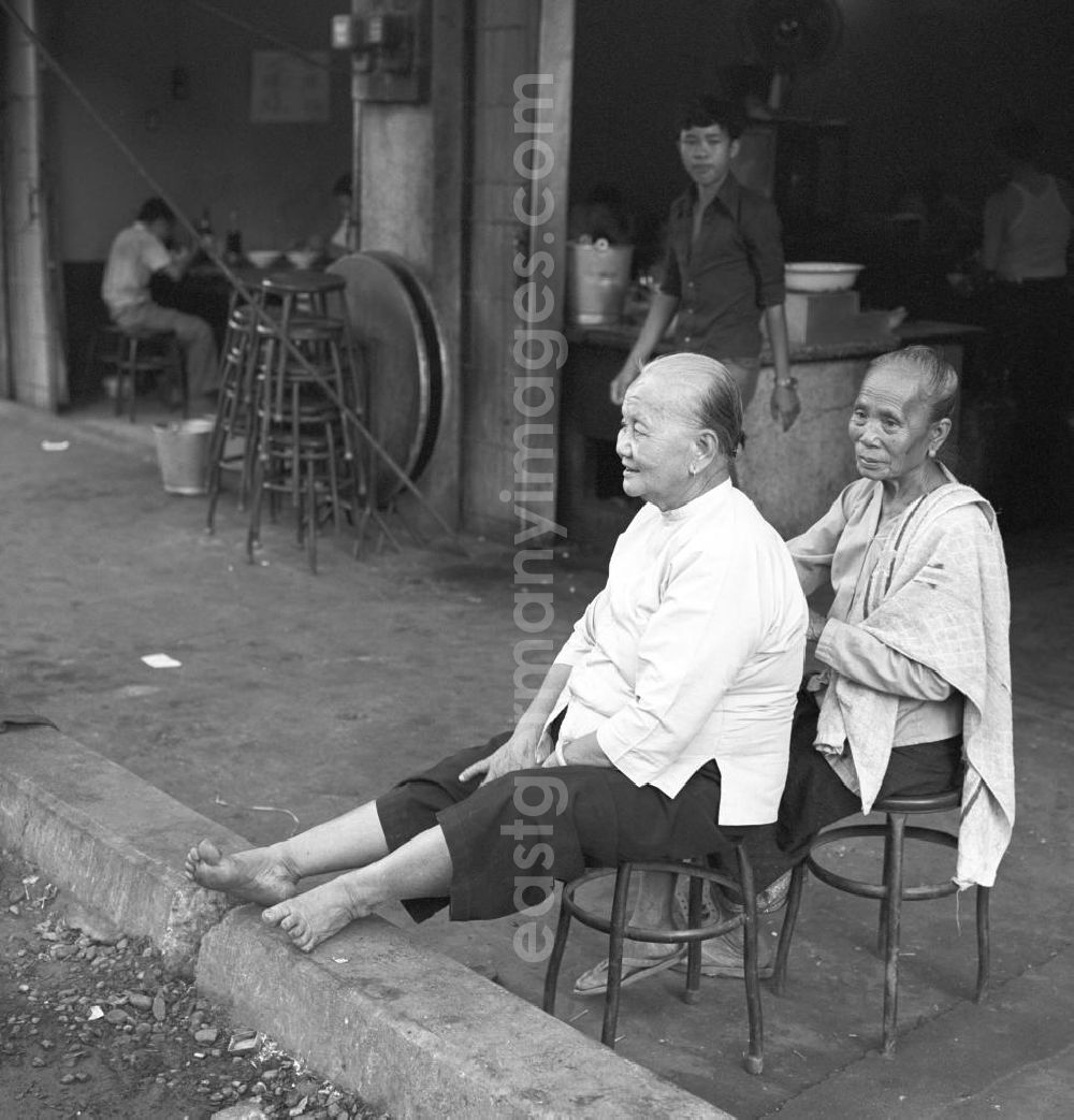 GDR picture archive: Vientiane - Zwei Frauen sitzen am Rand einer Straße in Vientiane, der Hauptstadt der Demokratischen Volksrepublik Laos.
