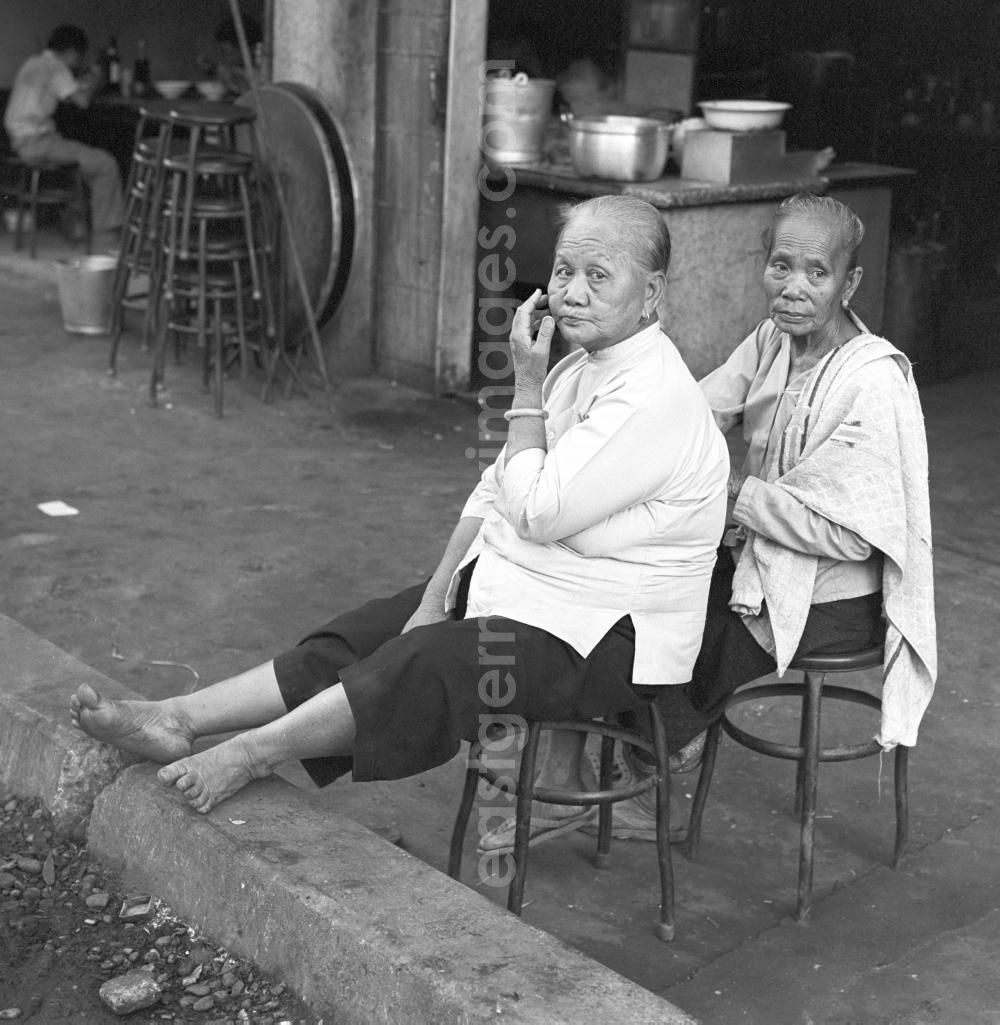 GDR image archive: Vientiane - Zwei Frauen sitzen am Rand einer Straße in Vientiane, der Hauptstadt der Demokratischen Volksrepublik Laos.