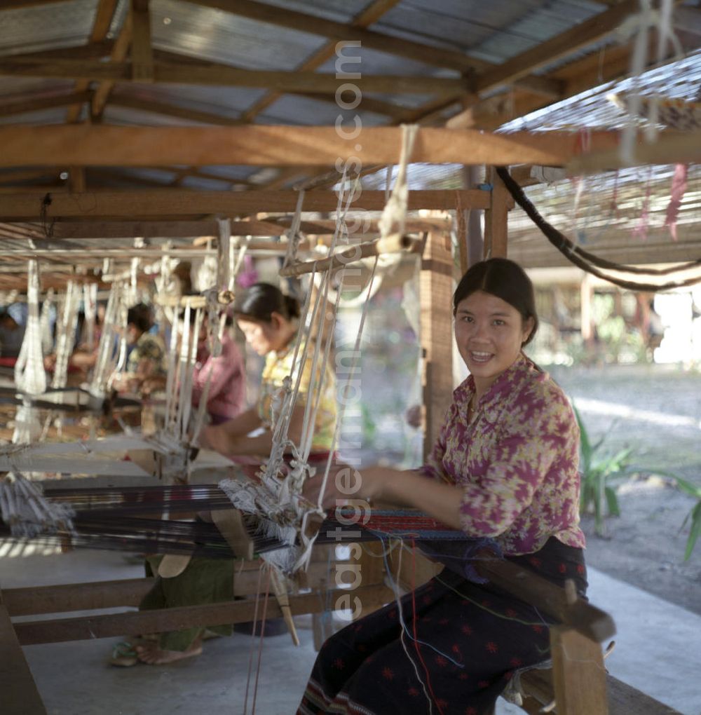 GDR photo archive: Vientiane - Frauen weben an Holzwebstühlen in einer Weberei in Vientiane, der Hauptstadt der Demokratischen Volksrepublik Laos.