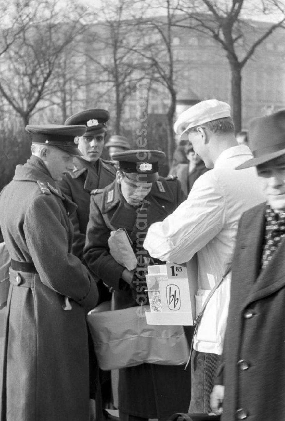 GDR photo archive: Leipzig - Angehörige der NVA schauen interessiert auf Taschenbücher des Aufbau Verlages, die ein Verkäufer mit Bauchladen in Leipzig anbietet. Mit der Folge bb für Billige Bücher rief der größte belletristische Verlag der DDR 1958 seine erste Taschenbuchreihe ins Leben.