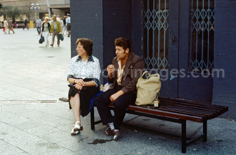 GDR picture archive: Berlin - A woman and a man sit smoking on a street bench in East Berlin in the territory of the former GDR, German Democratic Republic