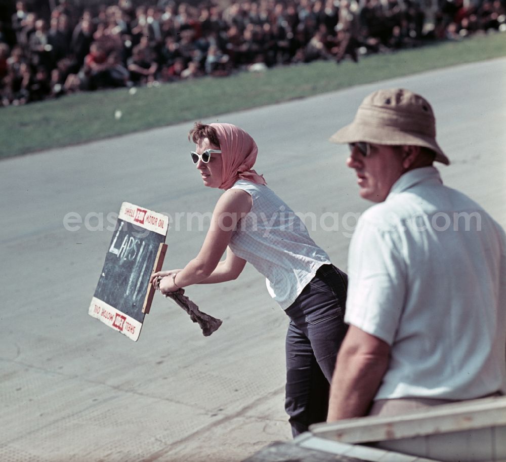 GDR image archive: Hohenstein-Ernstthal - A woman holds a board with the number of laps on the race track during the race at the motorcycle race on the Sachsenring in Hohenstein-Ernstthal, Saxony in the territory of the former GDR, German Democratic Republic