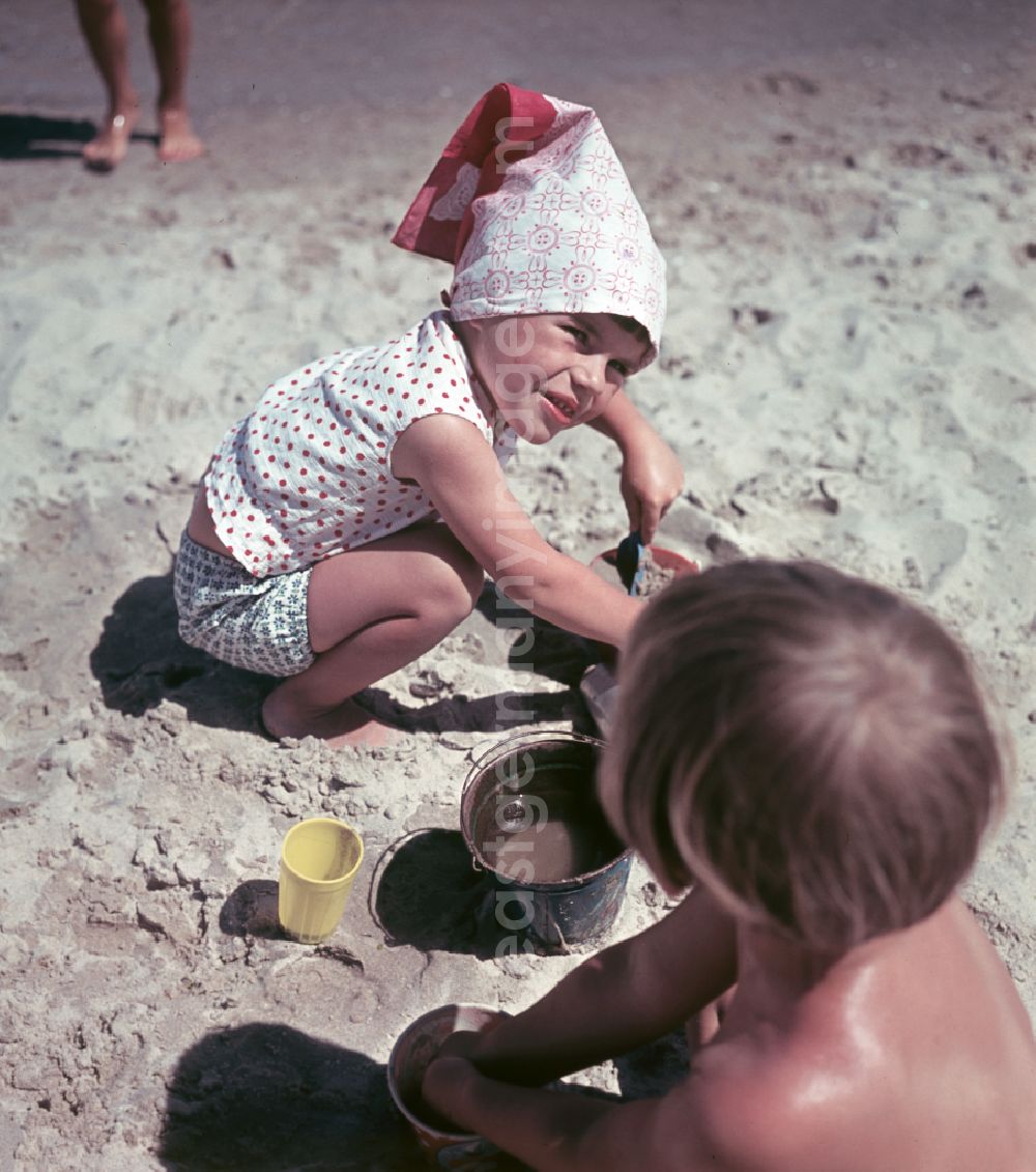 GDR photo archive: Binz - Little girl with headscarf digs on the sandy beach of the Baltic Sea during her Baltic Sea vacation in Binz, Mecklenburg-Western Pomerania in the territory of the former GDR, German Democratic Republic