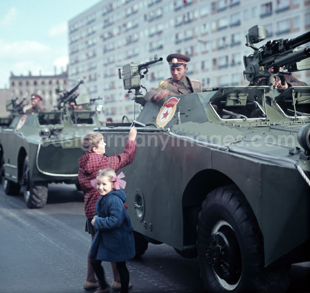 GDR photo archive: Berlin - Enthusiastic population forming a guard of honor for the parade drive of military and combat technology Armored infantry vehicle SPW BRDM-1 on Lichtenberger Strasse in the district of Friedrichshain in East Berlin in the territory of the former GDR, German Democratic Republic