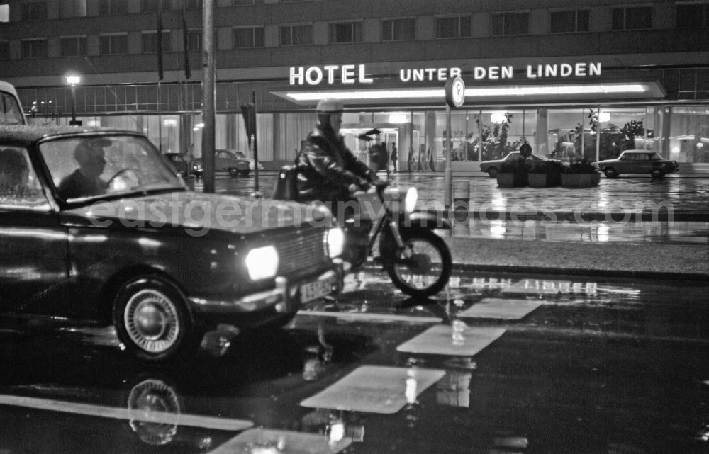 GDR image archive: Berlin - Car - motor vehicle in nighttime and rainy traffic Wartburg 311 and MZ motorcycle in front of the Hotel Unter den Linden on Friedrichstrasse in the Mitte district of Berlin East Berlin on the territory of the former GDR, German Democratic Republic