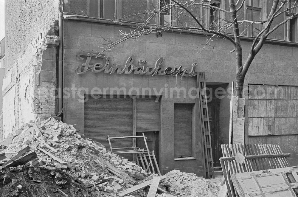 GDR photo archive: Berlin - Fading lettering in the entrance area and shop window of a retail store Feinbaeckerei in the demolition street area of an old residential building facade on Colbestrasse in the district of Friedrichshain in Berlin East Berlin in the area of the former GDR, German Democratic Republic