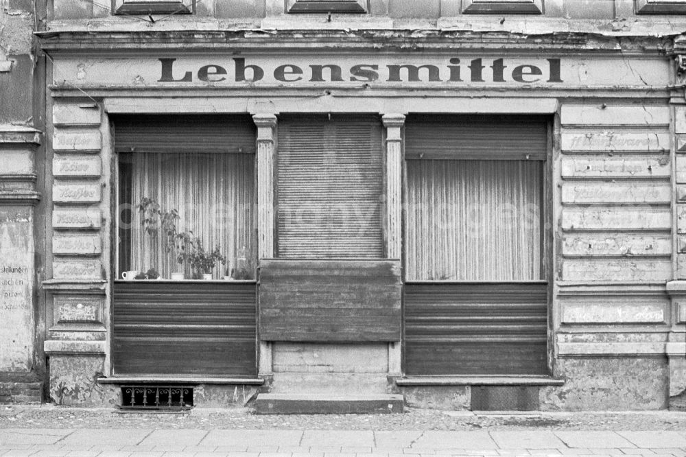 GDR picture archive: Berlin - Fading lettering in the entrance area and shop window of a retail store Lebensmittel in the street area of an old residential building facade on street Jessnerstrasse in the district Friedrichshain in Berlin Eastberlin on the territory of the former GDR, German Democratic Republic