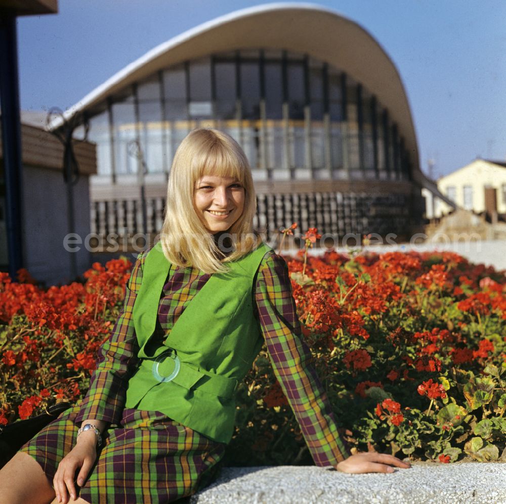 GDR photo archive: Rostock - A young woman sits on the edge of a flower bed in front of the Teepott in the district of Warnemuende in Rostock, Mecklenburg-Vorpommern in the area of the former GDR, German Democratic Republic