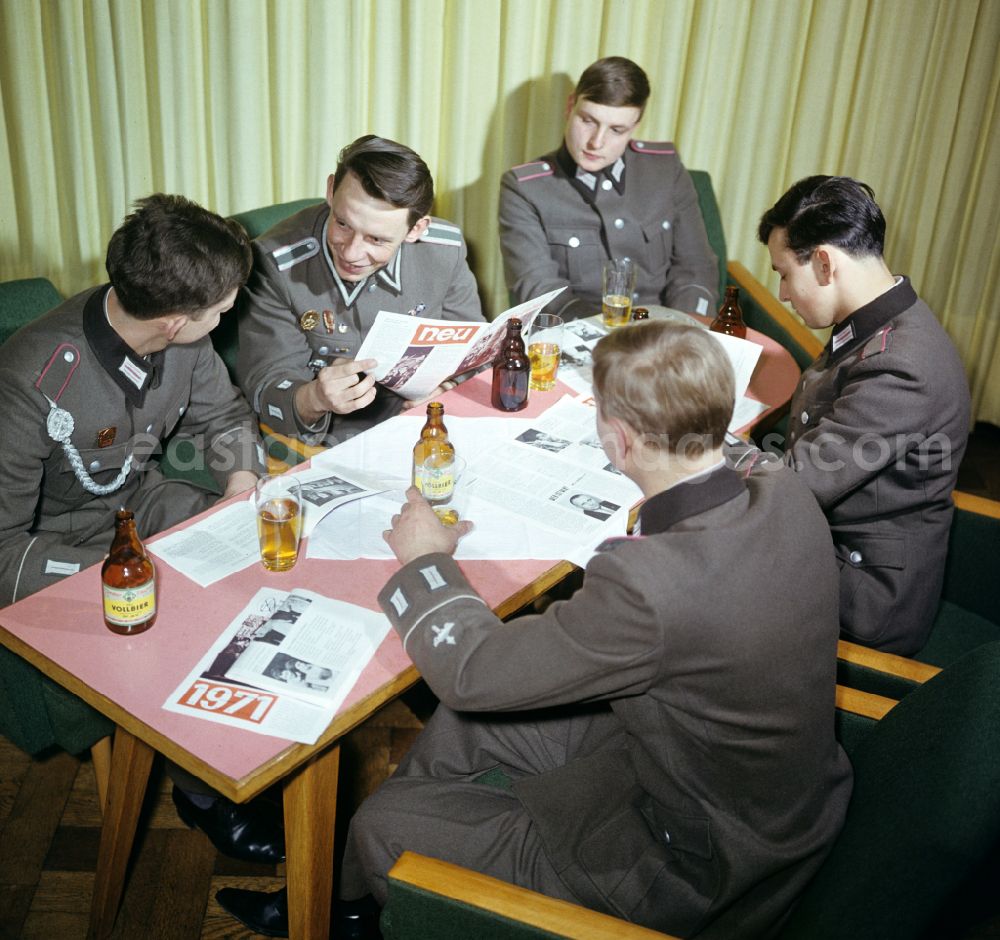 GDR photo archive: Oranienburg - Soldiers - equipment and uniforms of the land forces of the NVA National Peoples Army in their free time reading the newspaper and drinking beer in the common room in a barracks accommodation in Oranienburg, Brandenburg in the territory of the former GDR, German Democratic Republic