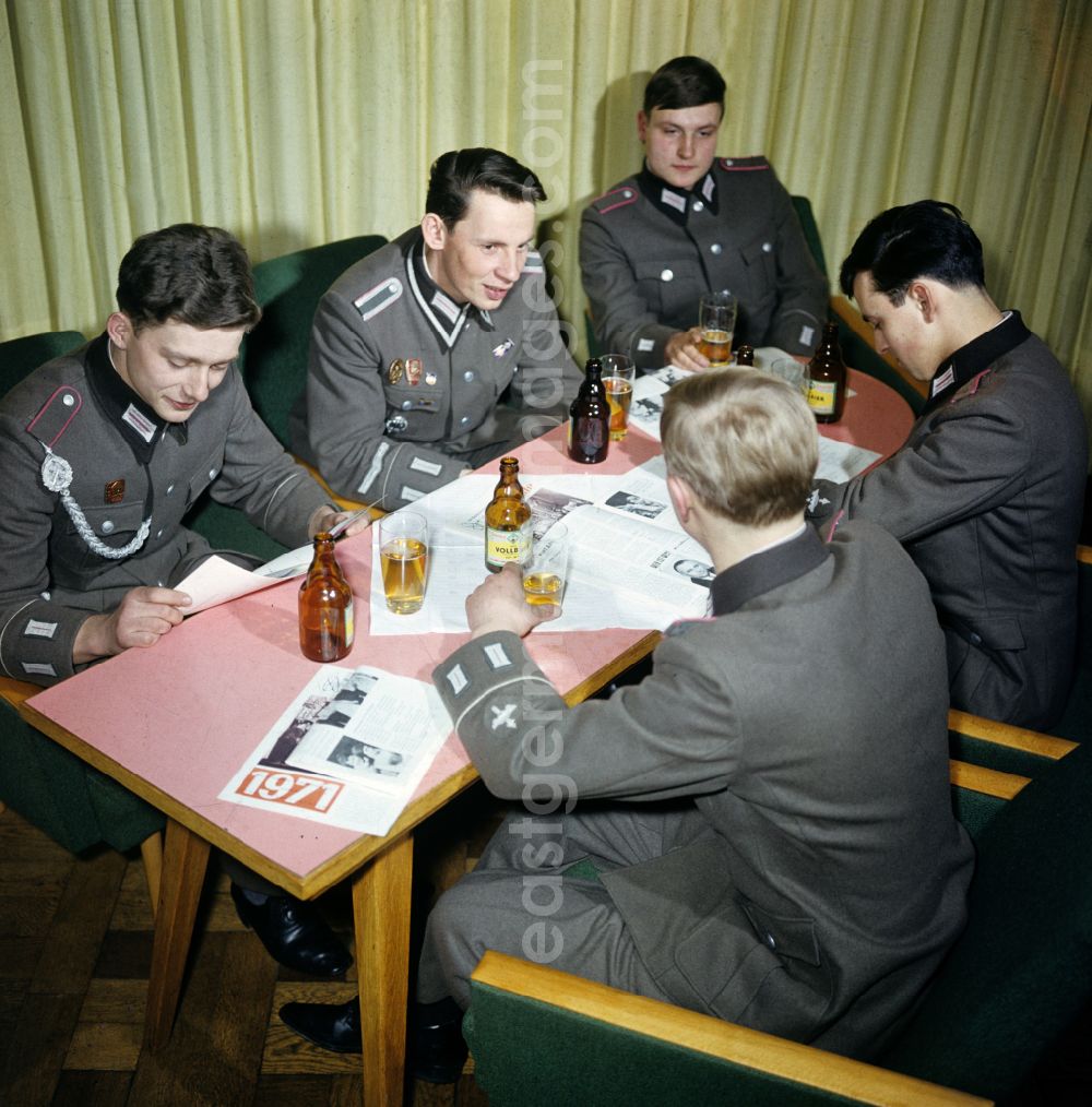 Oranienburg: Soldiers - equipment and uniforms of the land forces of the NVA National Peoples Army in their free time reading the newspaper and drinking beer in the common room in a barracks accommodation in Oranienburg, Brandenburg in the territory of the former GDR, German Democratic Republic