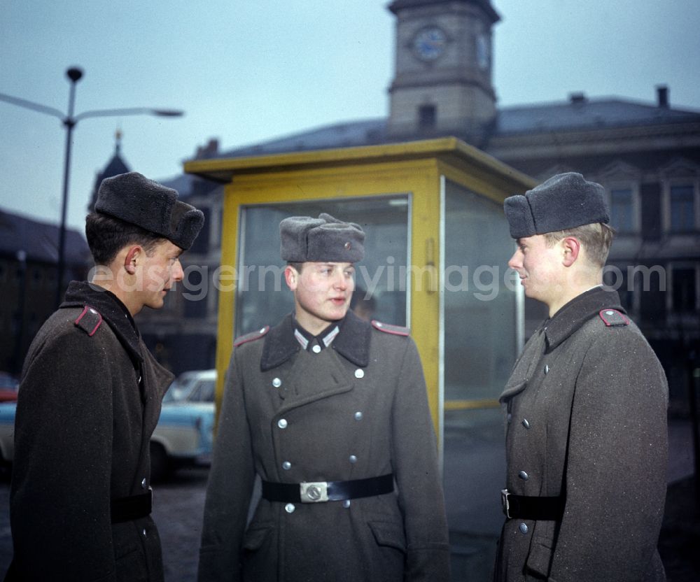 GDR picture archive: Oranienburg - Soldiers - equipment and uniforms of the land forces of the NVA National Peoples Army in their free time at the exit in front of a telephone booth of the German Post Office after calling home in Oranienburg, Brandenburg in the territory of the former GDR, German Democratic Republic