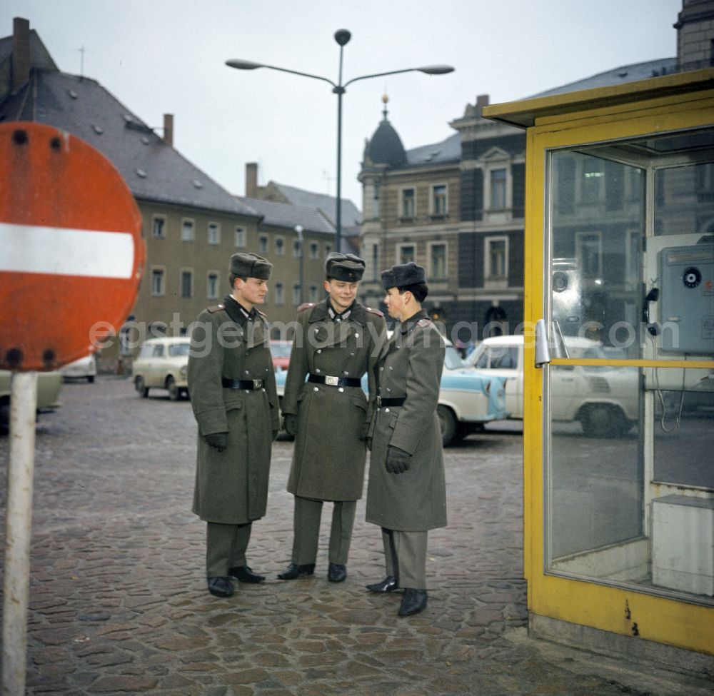 Oranienburg: Soldiers - equipment and uniforms of the land forces of the NVA National Peoples Army in their free time at the exit in front of a telephone booth of the German Post Office after calling home in Oranienburg, Brandenburg in the territory of the former GDR, German Democratic Republic