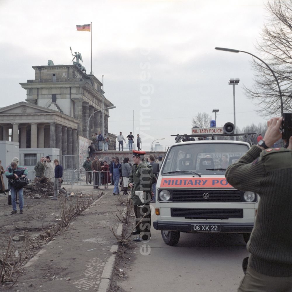 GDR photo archive: Berlin - A British officer with 2 members of the Royal Military Police as soldiers of the Allied occupying forces observe and photograph the demolition of the Berlin Wall in Mitte in East Berlin on the territory of the former GDR, German Democratic Republic