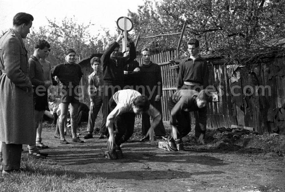 GDR photo archive: Leipzig - Zwei Leichtathleten beim Start. Im Hintergrund ein Mann, der das Startzeichen gibt. Um die Atlethen stehen männliche Zuschauer in Freizeit - bzw. Sportkleidung. Bestmögliche Qualität nach Vorlage!