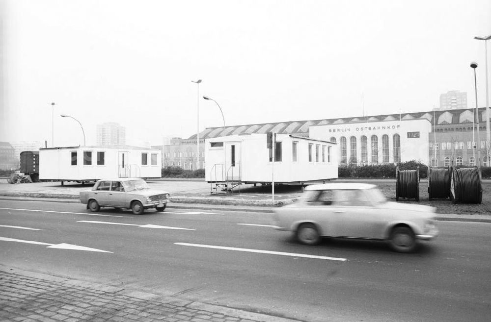 GDR picture archive: Berlin - Blick über Strasse auf der Autos vom Typ Lada und Trabant fahren, auf das mit Bauarbeiterunterkünften / Bauwagen / Bauhänger vollgestellte Vorfeld / Vorplatz am Berliner Ostbahnhof in Berlin-Friedrichshain.