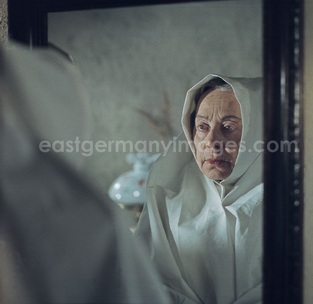 Ortschaft Heide: Scene from the film and television production Film: Rublak - The Legend of the Surveyed Land in the town of Heide, Saxony in the area of the former GDR, German Democratic Republic. An old farmer's wife in mourning looks into a mirror. The actress Doris Thalmer as a Sorbian farmer's wife in white costume