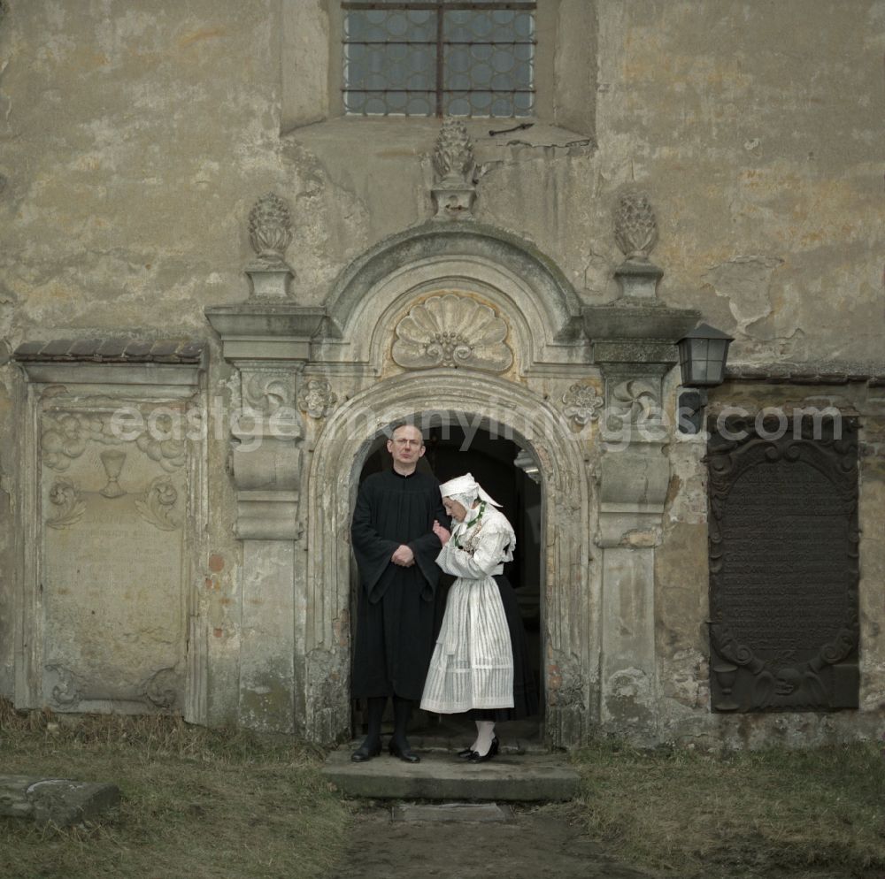 GDR picture archive: Kreba-Neudorf - Scene from the film and television production Continent Hope with the actress Majka Kowarjec and the actor Alfred Luebke at the entrance of a church in Kreba-Neudorf, Saxony in the area of the former GDR, German Democratic Republic