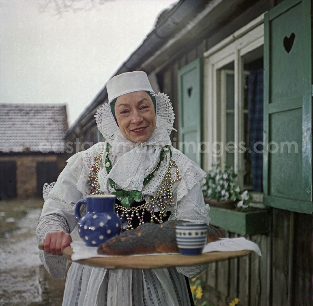 GDR photo archive: Kreba-Neudorf - Scene from the film and television production Continent Hope with the actress Majka Kowarjec in Sorbian costume as a mother in front of an old farm in Kreba-Neudorf, Saxony in the area of the former GDR, German Democratic Republic