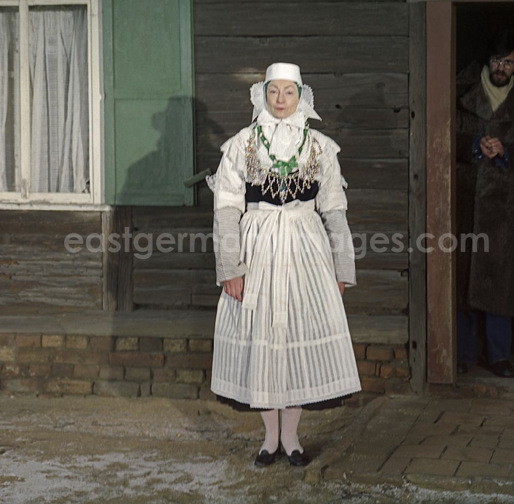 GDR picture archive: Kreba-Neudorf - Scene from the film and television production Continent Hope with the actress Majka Kowarjec in Sorbian costume as a mother in front of an old farm in Kreba-Neudorf, Saxony in the area of the former GDR, German Democratic Republic