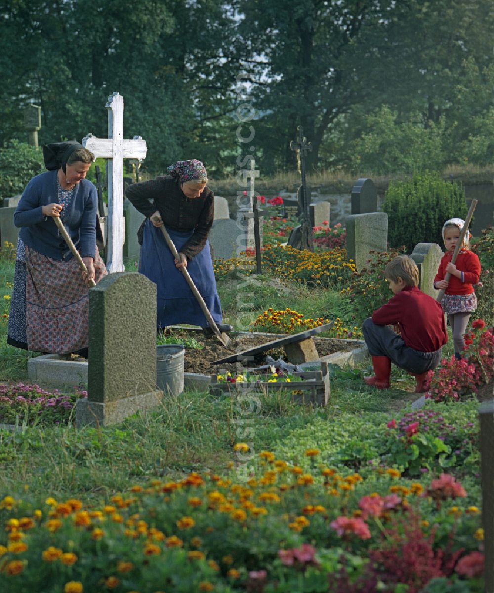 GDR picture archive: Ralbitz - Scene from the film and television production Portrait of a Center in front of grave crosses and cemetery stones of a Sorbian cemetery on the main street in Ralbitz, Saxony in the area of the former GDR, German Democratic Republic